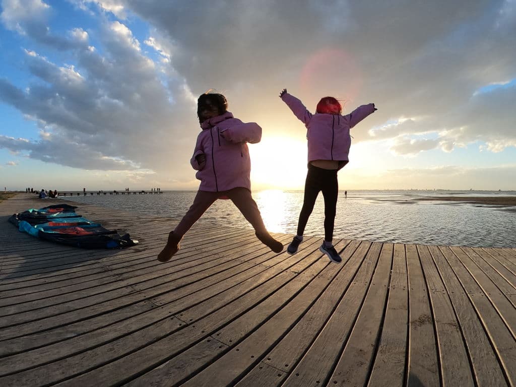 Las mellizas saltando de alegría en un muelle al atardecer